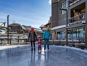 Enjoy ice skating on a frozen rink surrounded by snow, with a nearby building offering a warm retreat.