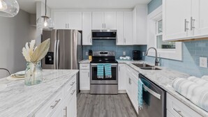 Una cocina moderna con gabinetes blancos, electrodomésticos de acero inoxidable y un salpicadero de azulejos azules.