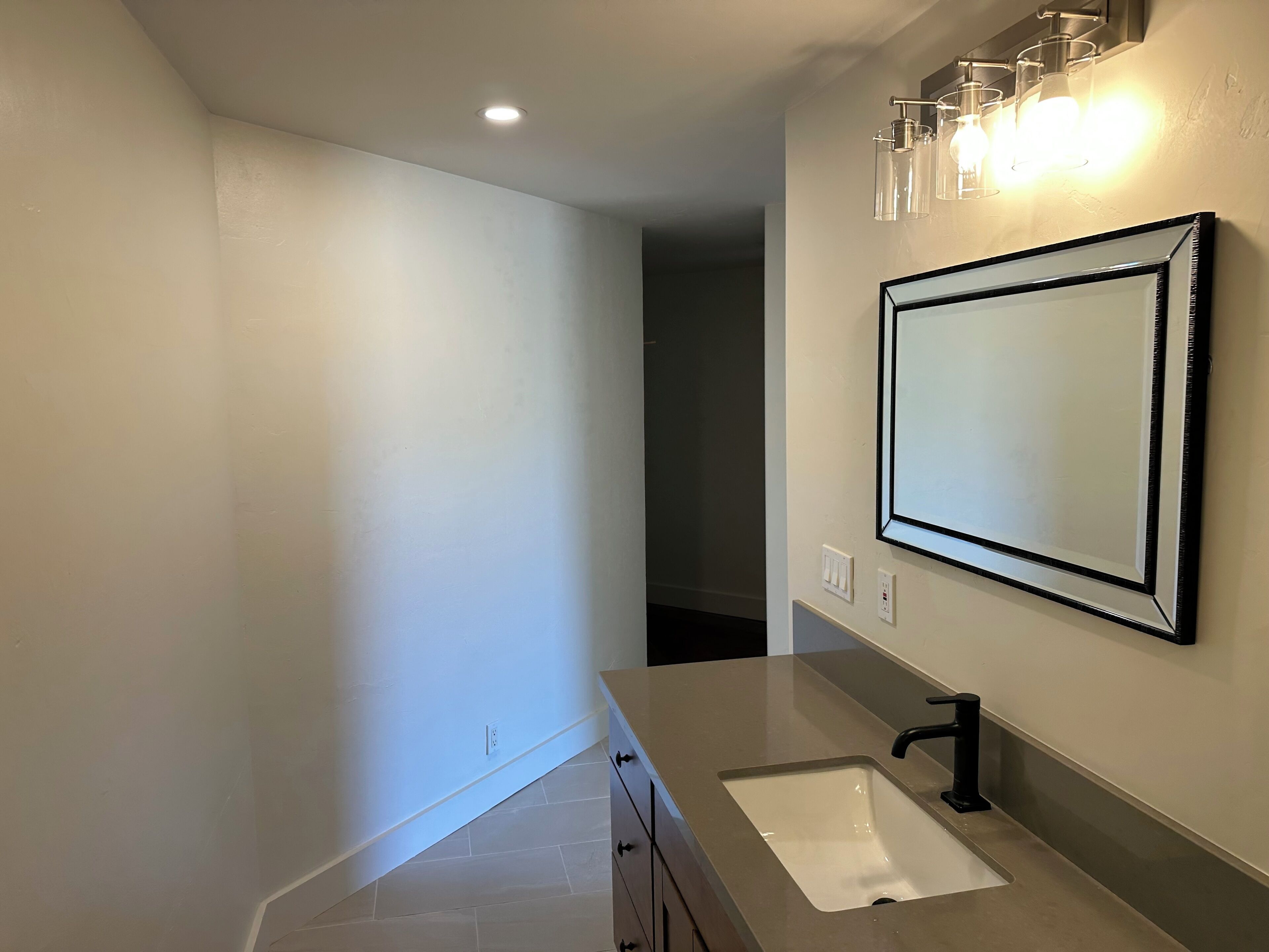 A modern bathroom with a large mirror, a sink, and a countertop.