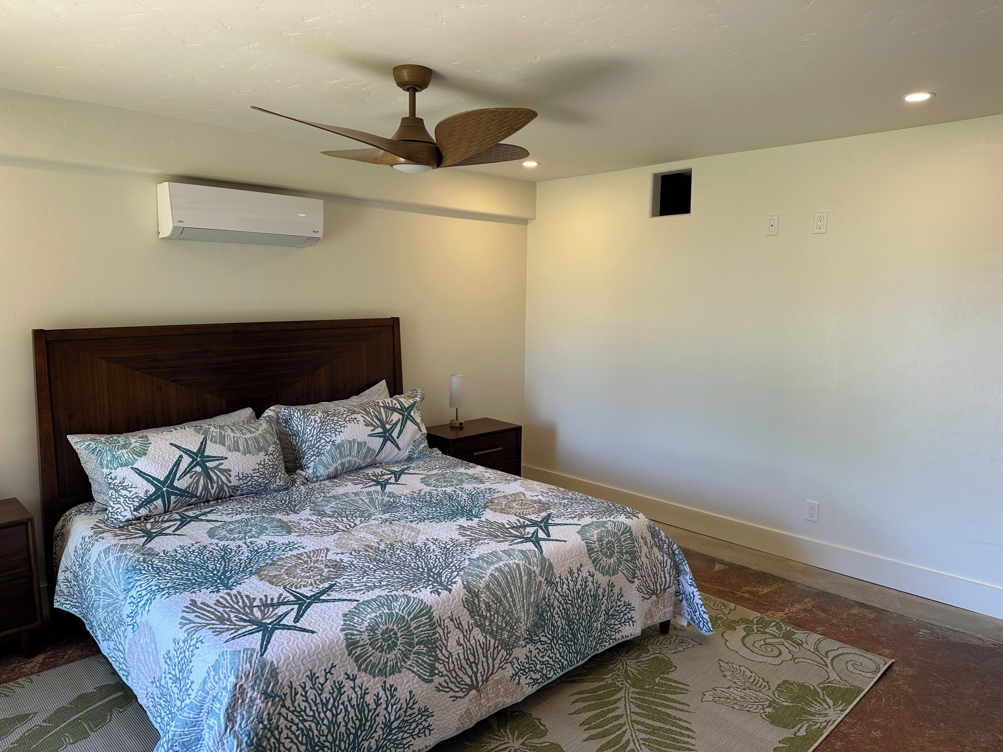 A bedroom with a bed, a ceiling fan, a nightstand, and a night lamp.