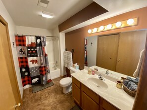 A bathroom with a shower curtain featuring animal prints, a toilet, a sink with a mirror above it, and a vanity with a towel rack. - Black Bear Traditions-Relaxing north woods getaway-Little St. Germain Lake (Saint Germain)