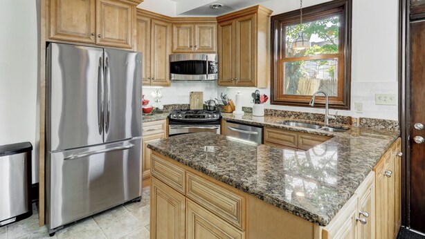 A kitchen with wooden cabinets, stainless steel appliances, granite countertops, and a window with a view. - The Shipoke Brickhouse (Harrisburg)