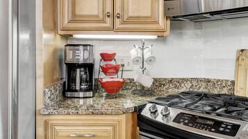 A kitchen with a coffee maker, a stove, and a microwave.