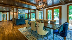 A spacious living area with a stone fireplace, large windows, and a dining table with chairs. - Magnificent 7bdrm 8bath luxury on Lake Joe! Hot Tub! Gym! Boathouse! Sauna! (Seguin)