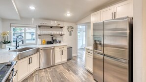 A modern kitchen with stainless steel appliances, white cabinetry, and a wooden floor. - 1905 Farmhouse w/ Fresh Make Over ☼ 3 BR / 2 BA (Mountlake Terrace)