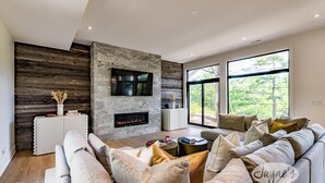A modern living room with a fireplace, large windows, and a cozy seating area.