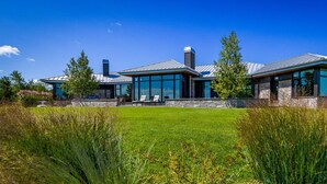 A modern two-story house with large glass windows, a stone facade, and a well-maintained lawn. - 3 bdrm, 3 bath Country Home, 10 acres, private, hot tub, view of Georgian Bay! (Bruce Peninsula (Wiarton) Thornbury)