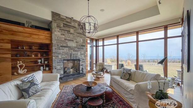 A spacious living room with a stone fireplace, large windows, and a view of the outdoors. - 3 bdrm, 3 bath Country Home, 10 acres, private, hot tub, view of Georgian Bay! (Bruce Peninsula (Wiarton) Thornbury)