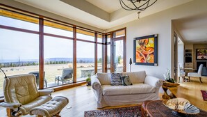 A spacious living room with a large window, a white sofa, a leather chair, and a traditional rug. - 3 bdrm, 3 bath Country Home, 10 acres, private, hot tub, view of Georgian Bay! (Bruce Peninsula (Wiarton) Thornbury)