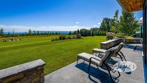 A patio with outdoor furniture overlooking a well-maintained lawn and a scenic view of a lake and mountains. - 3 bdrm, 3 bath Country Home, 10 acres, private, hot tub, view of Georgian Bay! (Bruce Peninsula (Wiarton) Thornbury)