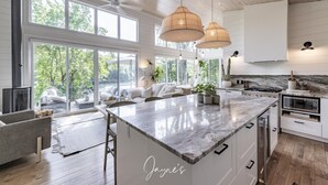 Una cocina moderna con una isla grande, armarios blancos e iluminación colgante.