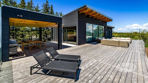 A modern outdoor deck with a dining area, lounge chairs, and a barbecue grill. - Lovely 5bdrm 3bath modern home in Creemore! (Creemore)
