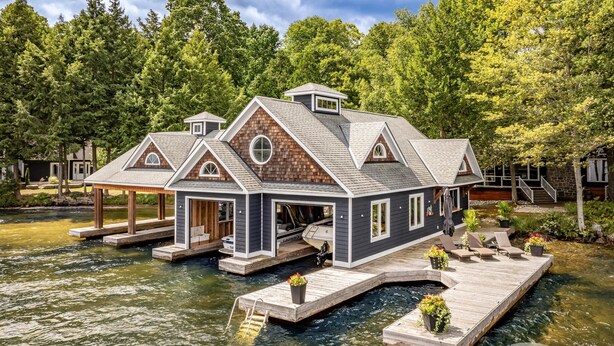 A houseboat with a dock, surrounded by water and trees. - 9 bdrm, 5 bath, Lake Rosseau, Private! Guest Cottage and Cabin! Sand Beach! (Port Carling)