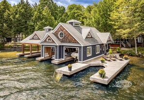 A houseboat with a dock, surrounded by water and trees. - 9 bdrm, 5 bath, Lake Rosseau, Private! Guest Cottage and Cabin! Sand Beach! (Port Carling)
