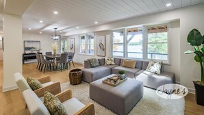 Una sala de estar moderna con comedor, ventanas amplias y vistas al exterior.