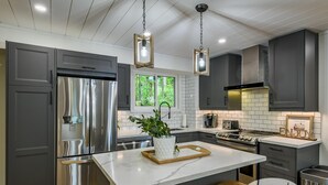 Una cocina moderna con electrodomésticos de acero inoxidable, una isla de mármol e iluminación colgante.