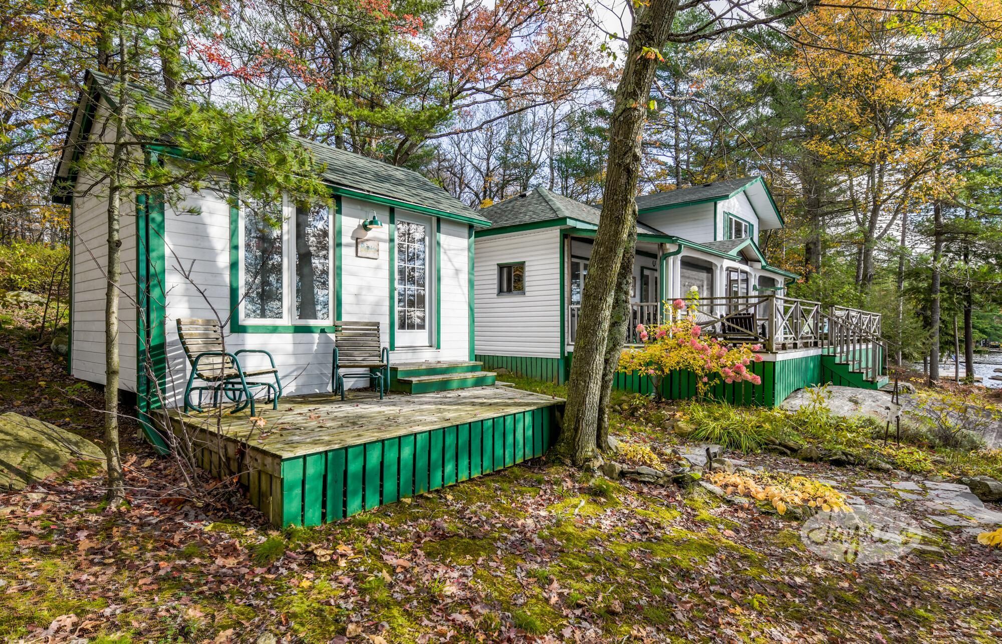 Eine Hütte mit Veranda und kleiner Terrasse, umgeben von Bäumen und einer felsigen Küste.