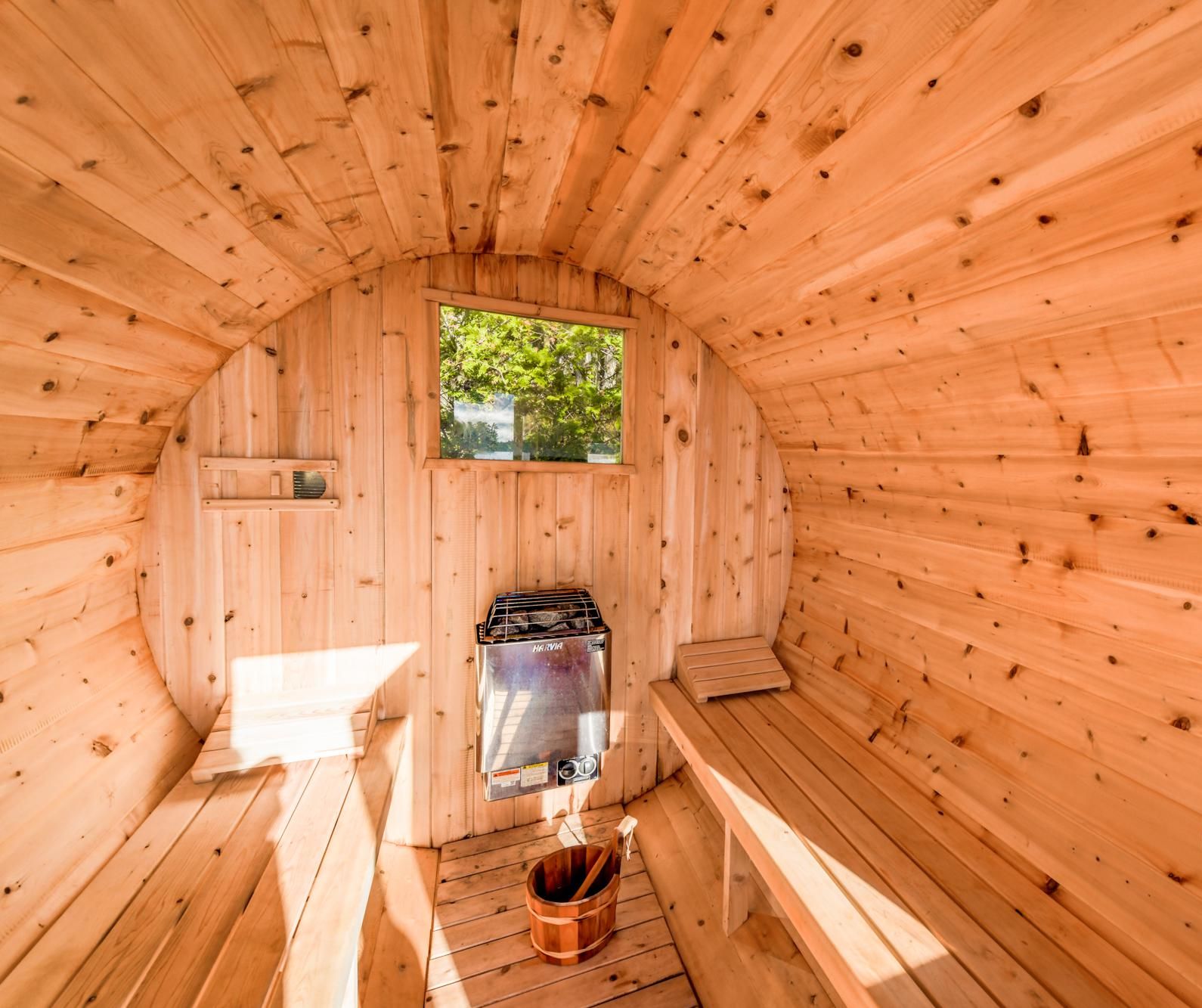 Un sauna en bois, avec un banc, un seau et un appareil de chauffage pour sauna.