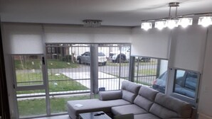 Ein modernes Wohnzimmer mit einem Ecksofa, einem Esstisch mit Stühlen und einem großen Fenster mit Blick auf die Straße.