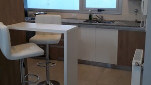 Eine kleine Küche mit weißer Arbeitsplatte, einem Spülbecken und einem Doppel-Fenster.