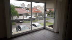 Ein Zimmer mit großen Fenstern und Blick auf eine Straße mit parkenden Autos und Häusern.