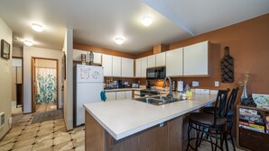 A modern kitchen with a central island, white cabinets, and a microwave.