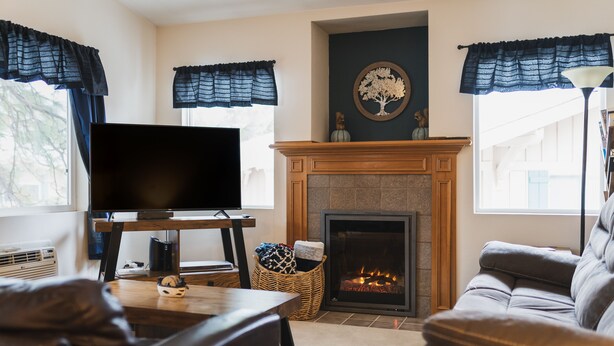 A living room with a fireplace, a television on a stand, and a sofa.