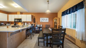 A modern kitchen with a central island, wooden cabinets, and a dining area with a wooden table and chairs.