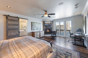 A bedroom with a bed, a fireplace, a desk, and a large window. - Ironwood by Luxury Mountain Destinations (Park City)