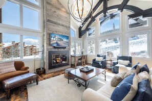 A spacious living room with a fireplace, large windows, and a cozy seating area. - Ironwood by Luxury Mountain Destinations (Park City)