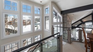 Un intérieur spacieux avec de grandes fenêtres, un escalier en bois et une cheminée en pierre.