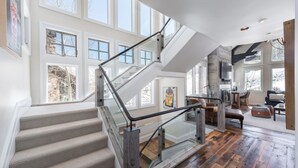 Un intérieur spacieux agrémenté d’un magnifique escalier, de grandes fenêtres et d’un espace cuisine moderne.