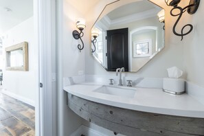 A bathroom with a white sink, a large mirror, and a wooden vanity. - Ironwood by Luxury Mountain Destinations (Park City)