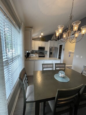 Enjoy meals in the spacious kitchen and dining area, featuring a central island, stainless steel appliances, and a rectangular dining table with four chairs.