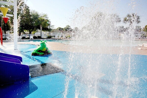 Enjoy a refreshing splash at the resort's water play area, featuring a large fountain and a fun green water slide for kids.