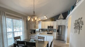 A modern kitchen with white cabinets, a central island, and stainless steel appliances. - Pelican Landing / Beach Bird Properties - Inside Oceanside Village (Surfside Beach)
