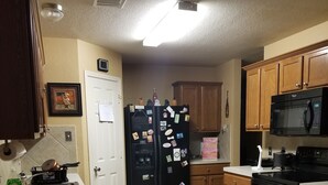 Una cocina con armarios de madera, un refrigerador negro, un microondas y una estufa.