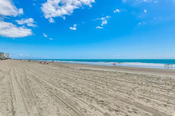 A wide sandy beach with footprints and a pier in the background. - South Bay INN (Myrtle Beach)