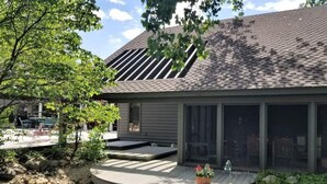 Una casa moderna con un porche cubierto, un pequeño estanque y un jardín.