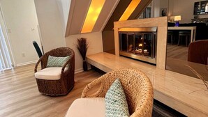 Una sala de estar moderna con chimenea, muebles de mimbre y un comedor al fondo.