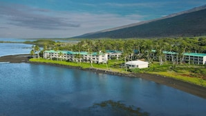 A resort with multiple buildings, a beachfront, and a mountainous backdrop. - September Sale! Molokai Island Retreat (Kaunakakai)