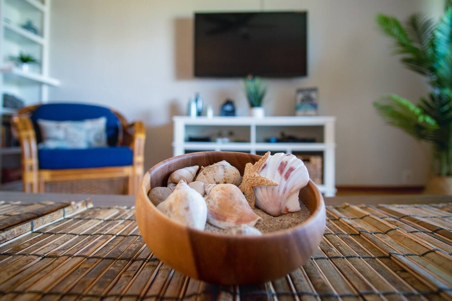 Eine Holzkreuzschiff gefüllt mit Muscheln und einem Seestern auf einer gewebten Matte.