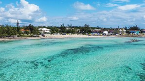 A coastal view with clear turquoise waters, beachfront properties, and lush greenery.