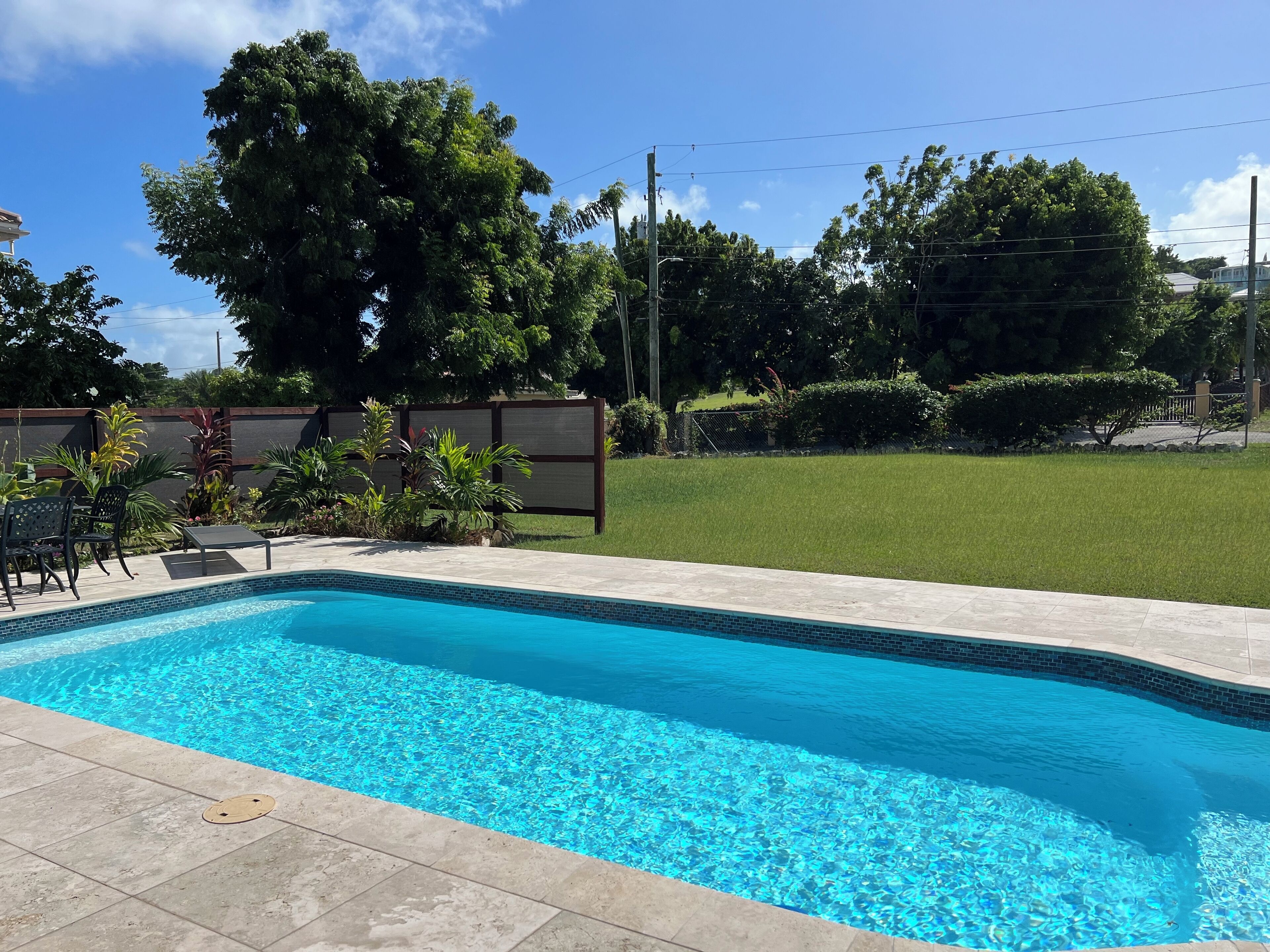 A rectangular swimming pool with clear blue water, surrounded by a tiled deck.