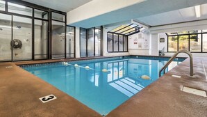 Una piscina interior amb parets de vidre transparent, aigua blava i una barra de socors.