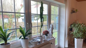 A bright room with large windows, a radiator, and several potted plants.