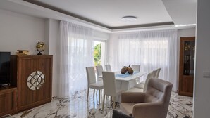 Een eetgedeelte met een witte tafel, vier stoelen en een houten kast met een decoratieve glazen deur.