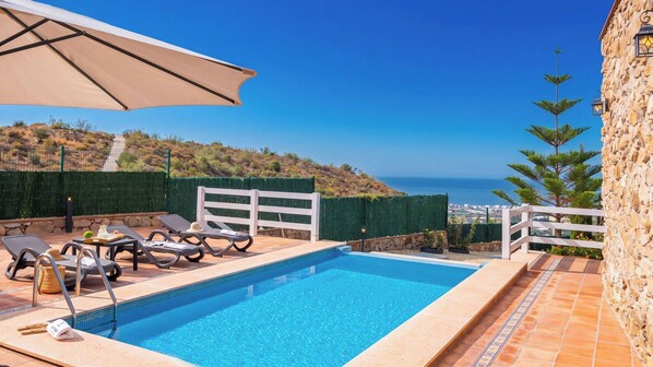 Una piscina con lettini e vista sul mare.