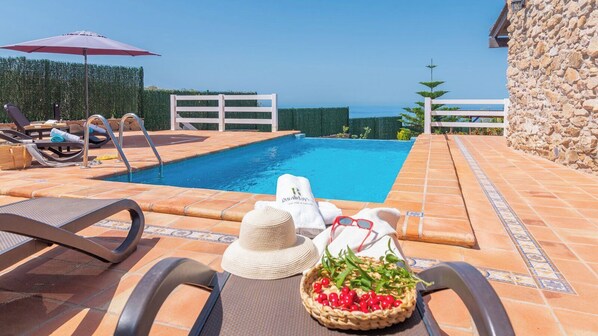A poolside area with lounge chairs, a pool, and a stone wall.