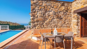 Un edificio de piedra con piscina, mobiliario exterior y vistas al mar.
